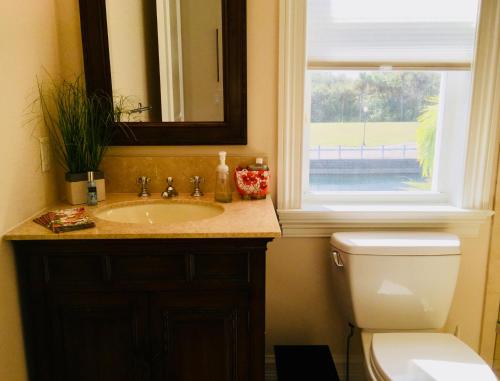 a bathroom with a sink and a toilet and a window at Avalon Beach in Fort Pierce