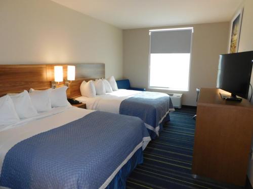 a hotel room with two beds and a flat screen tv at Days Inn & Suites by Wyndham Kearney NE in Kearney