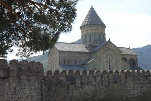 an old church with a tower behind a fence at Hotel Cité in Mtskheta