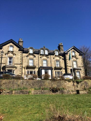 a large stone building on a hill with a green field at B/W Plus Buxton Lee Wood Hotel in Buxton