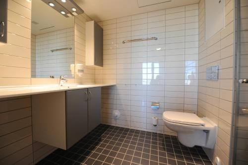 a bathroom with a toilet and a sink and a mirror at Tananger Apartment Hotel in Tananger