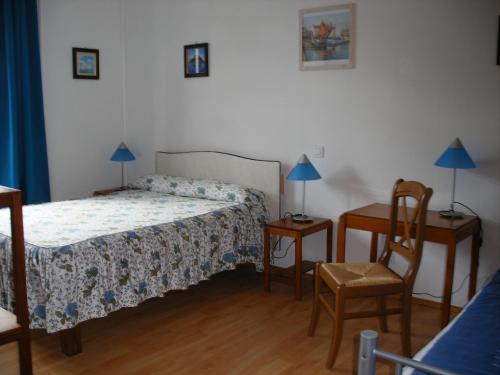 a bedroom with a bed and two tables and a chair at Hôtel Modern in Concarneau