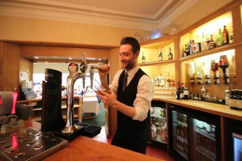 a man standing at a bar using his cell phone at B/W Plus Buxton Lee Wood Hotel in Buxton