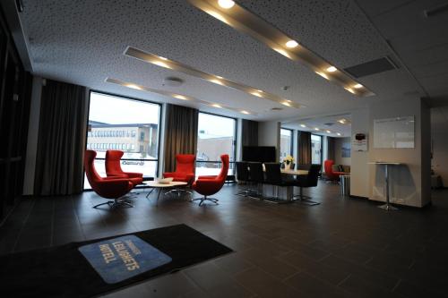 a lobby with red chairs and a table in a building at Tananger Apartment Hotel in Tananger
