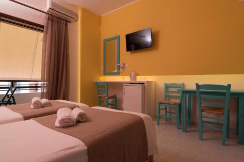 a hotel room with two beds and a table and chairs at Niki Rooms in Palaiochóra