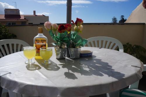 Una mesa blanca con una botella de vino y flores. en Casa Violeta, en Funchal