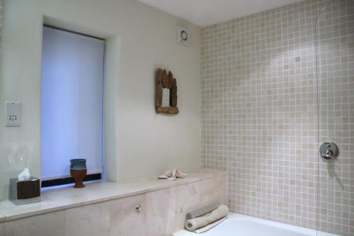 a bathroom with a tub and a tiled wall at Alston Art Apartments in Alston