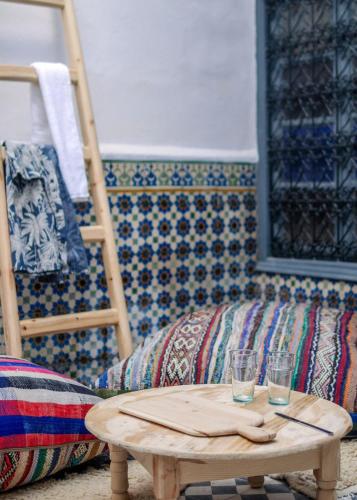 a table with two glasses and a couch in a room at Boho 27 Hostel Marrakech in Marrakech