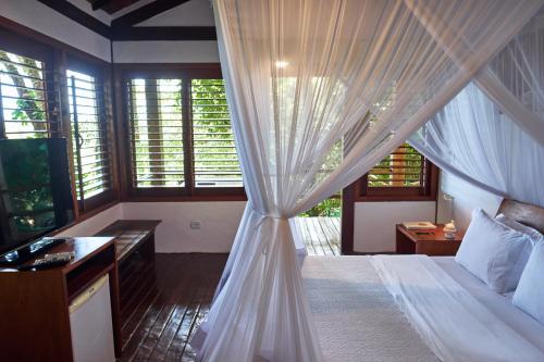 a bedroom with a canopy bed with a desk and a television at Pousada El Gordo in Trancoso