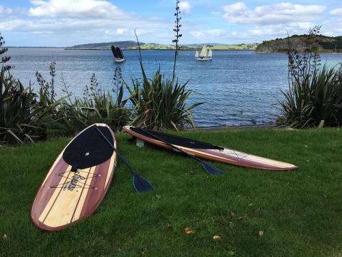 two kayaks sitting on the grass next to a body of water at Mason lane Apartment in Whangarei