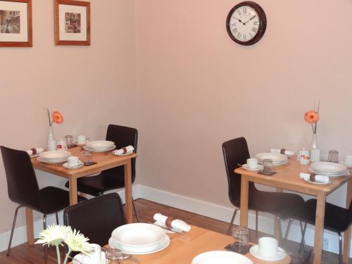 a dining room with two tables and a clock on the wall at Grange View Bed and Breakfast in Ayr