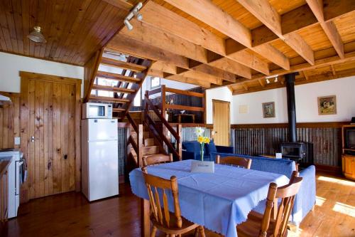 a kitchen and dining room with a table and a refrigerator at Sanctuary Park Cottages in Healesville