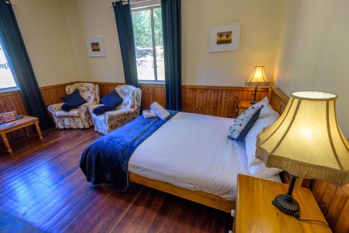 a bedroom with a large bed with a blue blanket on it at Lewana Cottages in Balingup