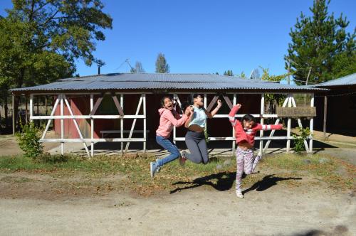 a group of three people jumping in the air at Coyunche Cabañas y Camping Laja & San Rosendo in Laja