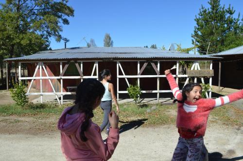two girls playing with a kite in front of a barn at Coyunche Cabañas y Camping Laja & San Rosendo in Laja