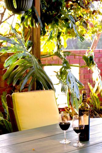 a bottle of wine and two glasses on a table at Bed & Breakfast at Tiffany's in McLaren Vale