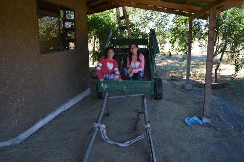 two girls are sitting in a green carousel at Coyunche Cabañas y Camping Laja & San Rosendo in Laja