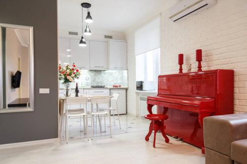 ein Wohnzimmer mit einem roten Klavier und eine Küche in der Unterkunft Lotos for You Apartments 2, RED PIANO in Mykolajiw