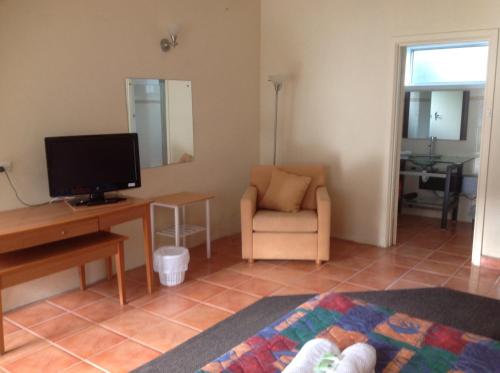 uma sala de estar com uma televisão e uma cadeira em Grampians Motel /Hotel em Dadswells Bridge