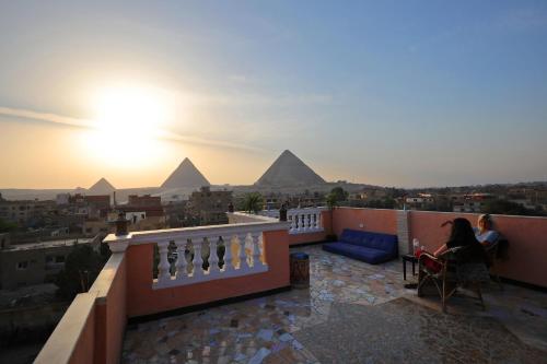 two people sitting on a balcony looking at the pyramids at Pyramids Loft Guesthouse in Cairo