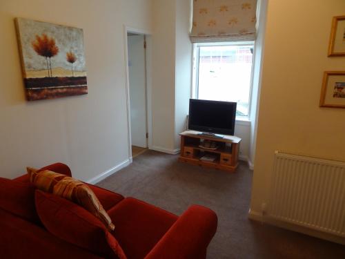 sala de estar con sofá rojo y TV en Grange View Bed and Breakfast, en Ayr