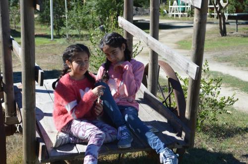 two children sitting on a slide at a playground at Coyunche Cabañas y Camping Laja & San Rosendo in Laja