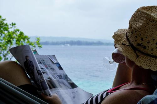 a woman sitting in a hammock reading a newspaper at Aoredise in Luganville