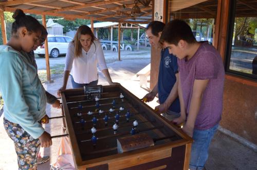 a group of people standing around a pool table at Coyunche Cabañas y Camping Laja & San Rosendo in Laja