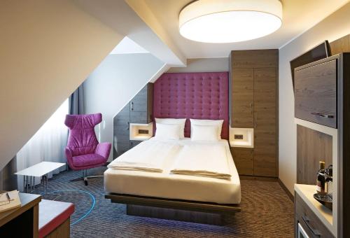 a hotel room with a bed and a purple headboard at Hotel Stadt München in Düsseldorf