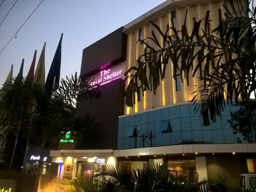 a building with a neon sign on the side of it at Hotel Royal Shelter in Vapi