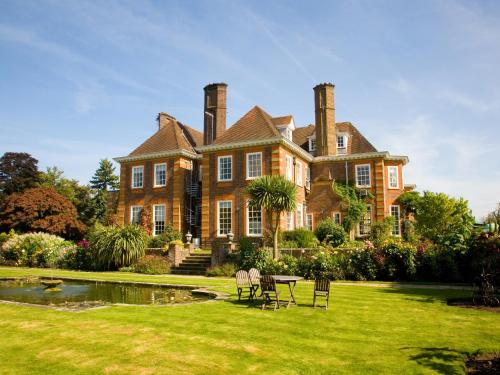 a large brick house with chairs in the yard at Barnett Hill Hotel in Guildford