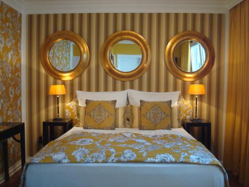 a bedroom with a bed with three mirrors on the wall at Hotel Sir & Lady Astor in Düsseldorf