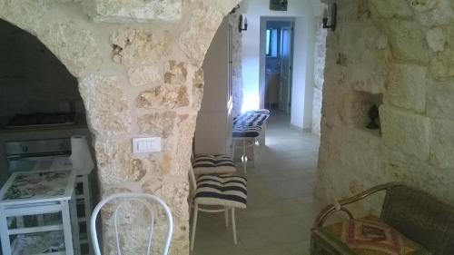 Habitación con un grupo de sillas contra una pared de piedra. en Trullo saraceno, en Ostuni