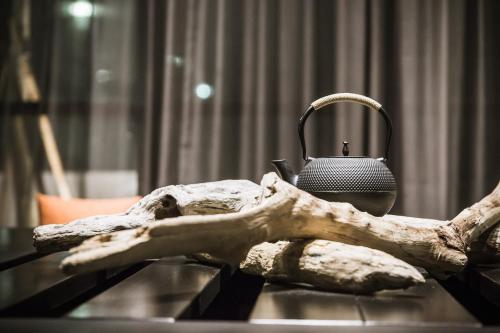 a table with a branch and a tea kettle on top at Tiin Tinn - Rivershore B&B in Taitung City