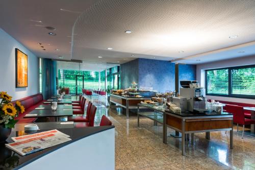 ein Restaurant mit langen Tischen und roten Stühlen in der Unterkunft Parkhotel Schillerhöhe in Marbach am Neckar