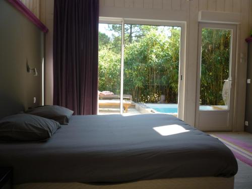 - une chambre avec un grand lit et une porte coulissante en verre dans l'établissement Un Matin D’été, à Lacanau-Océan