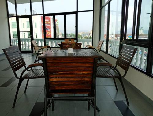 einen Tisch und Stühle in einem Zimmer mit Fenstern in der Unterkunft Oscar Suites Hotel in Sitiawan