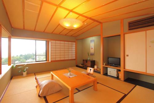a living room with a table and a tv at Nasubi no Hana in Ito
