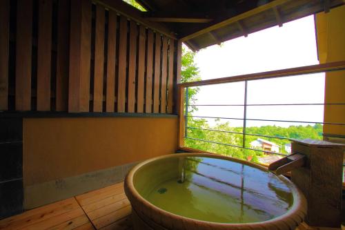 a large bath tub in a room with a window at Nasubi no Hana in Ito