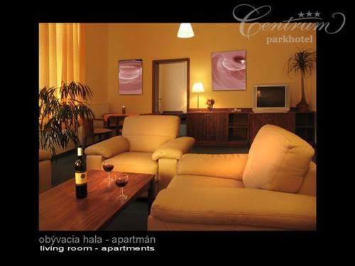 Parkhotel Centrum في سبيشسكا نوفا فيس: غرفة معيشة مع كنبتين وزجاجة من النبيذ