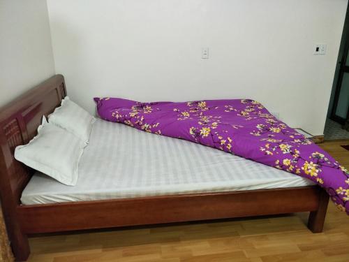 a bed with a purple blanket on top of it at Ngan Ha Homestay in Ha Giang