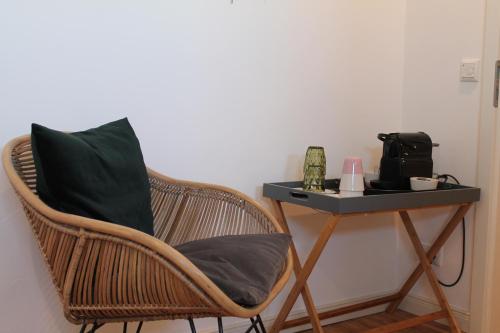 a wicker chair sitting next to a side table at Haus & Hof Guest House in Perl