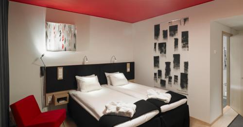 a bedroom with a black and white bed and a red chair at Kosta Boda Art Hotel in Kosta