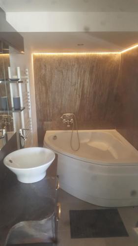 une salle de bain avec une baignoire et un lavabo dans l'établissement Charmant Appartement Neuf Le Taoume, à Éoures