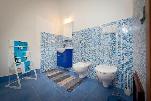 bagno piastrellato blu con servizi igienici e lavandino di Il Sole di Sicilia a Castellammare del Golfo