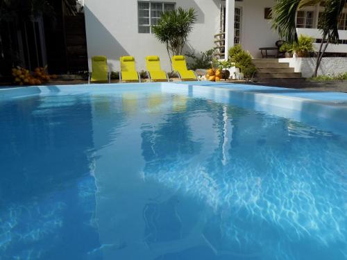 a swimming pool with chairs in a house at Villa Osumare Guest House in Flic-en-Flac
