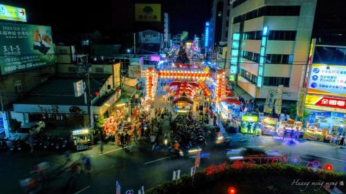 Una calle concurrida de noche con luces de Navidad en Shiah Yih Hotel, en Huwei