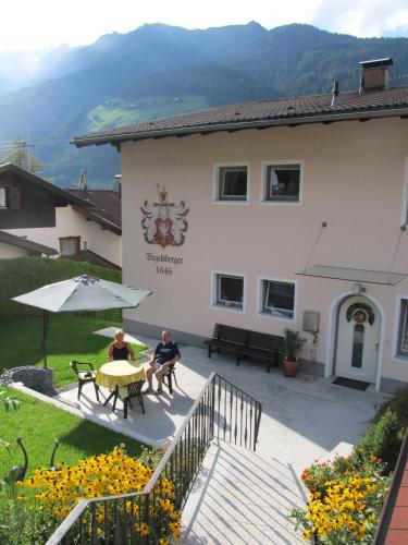 two people sitting at a table in front of a building at Haus Vogelsberger in Fulpmes