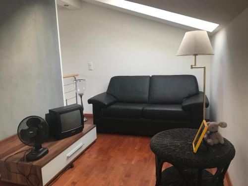 a living room with a black couch and a tv at FeWo mit Seeblick in Bodensdorf