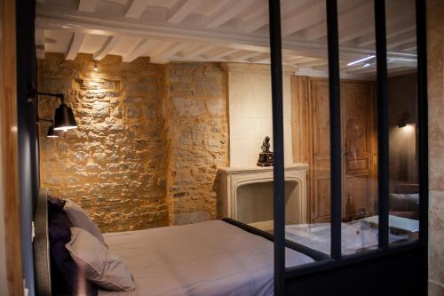 a bedroom with a bed and a stone wall at Villa Des Ursulines in Bayeux